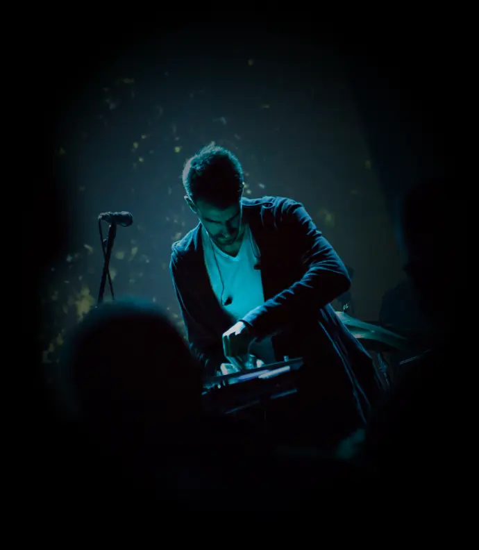 Homme dans le noir éclairé par une lumière bleue utilisant une table de mixage